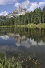 Reflections of pine trees and mountain peak in the lake Lago d'Antorno near Misurina in the