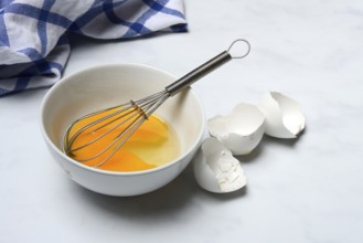 Whipped egg in shell with whisk, egg shells