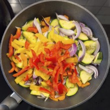 Vegetarian vegan dish Vegetable pan with courgettes red yellow peppers onions vegetable onions