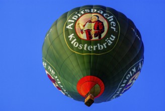 A hot air balloon with advertising for Alpirsbacher Klosterbräu takes to the air with passengers on