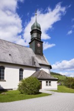 Church tower of St. Johann Church under a blue sky with cumulus clouds in the Innerlehen district,