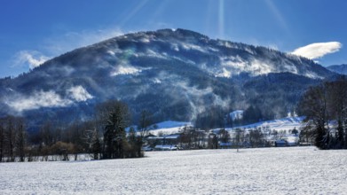 Snow-covered landscape with mountains under a blue sky and rays of sunshine, Bad Feilnbach