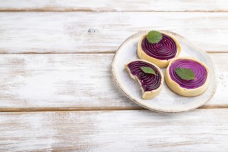 Sweet tartlets with jelly and milk cream on a white wooden background. Side view, copy space