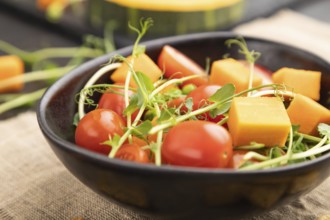 Vegetarian vegetable salad of tomatoes, pumpkin, microgreen pea sprouts on black concrete