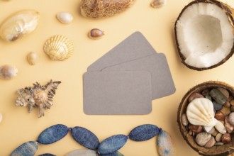 Brown paper business card with coconut, seashells, pebbles, beads on orange pastel background. Top