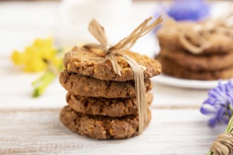 Oatmeal cookies with spring snowdrop flowers bluebells, narcissus and cup of coffee on white wooden