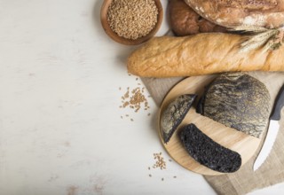 Sliced bread with different kinds of fresh baked bread on a white wooden background. top view, flat