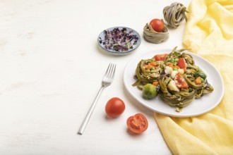 Tagliatelle green spinach pasta with tomato, pea and microgreen sprouts on a white wooden