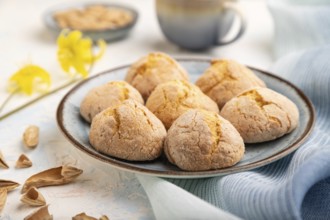 Almond cookies and a cup of coffee on a white concrete background and blue linen textile. Side