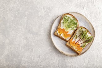 White bread sandwiches with cream cheese, calendula petals and microgreen on gray concrete