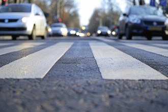 Close up of crosswalk on street with waiting cars in blurry background. Generative ai, AI generated