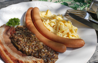 Swabian cuisine, lentils with spaetzle, pancetta and string sausages, meat arranged on a plate,