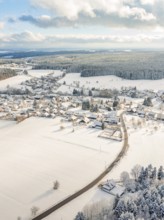 Snow-covered village with surrounding fields and hills in winter, Oberreichenbach, Black Forest,