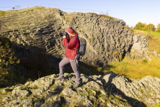 Photographer with camera and rucksack taking pictures at Hirtstein, Marienberg, Saxony, Germany,