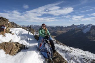 Mountaineer with rucksack taking a break on the Ramoljoch with snow, Ötztal Alps, Tyrol, Austria,