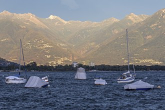 Boats lying in the water, Locarno, Lake Maggiore, surrounding mountains in the evening light,