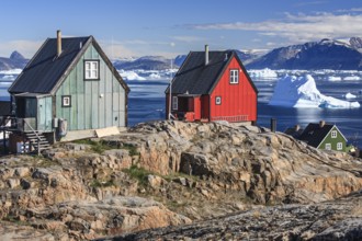 Typical Greenlandic houses in front of icebergs, Inuit settlement, summer, sunny, Uummannaq, West