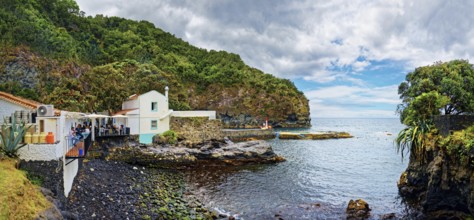 Fish restaurant in the small fishing village of Caloura on the rocky coast with lush greenery and