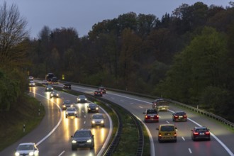 Cars driving on an illuminated motorway through a forest at dusk, Rems-Murr district,