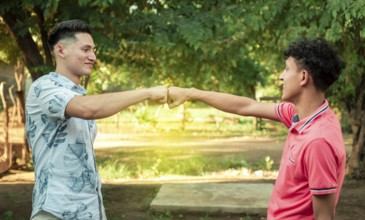 Two young men clashing their fists, image of two young men bumping their fists in a friendly way,