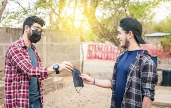 Concept of a person giving a surgical mask, Two young people giving each other a surgical mask,