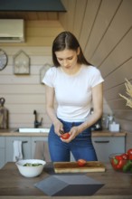 Young woman peels core of tomatoes while cooking a vegetable salad