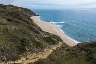 View of a coastal landscape with blue sea, cliffs and beach under a clear sky, Praia da Vigia,