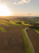 Sprawling fields in the evening light with a winding road under a warm glowing sunset, Gechingen,