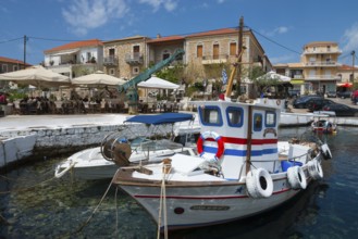 Traditional fishing boats in the harbour in front of a coastal town with historic buildings, Agios