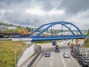 Blue painted bridge with construction workers and passing traffic, track construction, rail