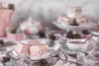 Pink glazed cakes, punch doughnuts surrounded by winter decorations and a coffee cup