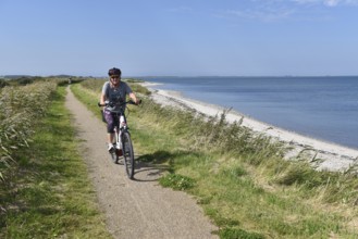 Woman, senior citizen cycling through Jutland in Denmark