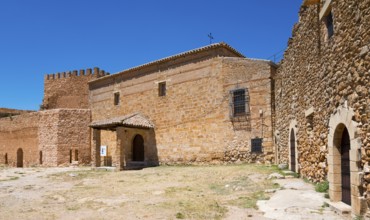 Historic stone structures with fortress wall and church rising under a clear sky, Castillo de