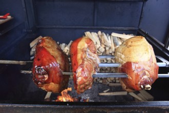 Pork knuckles are grilled on a spit over a wood fire