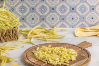 Sliced yellow beans on a wooden chopping board, whole runner beans in the background