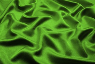 Green silk lies in soft, irregular folds