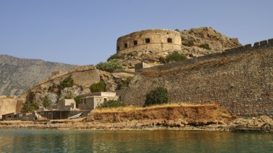 Ancient fortress with round tower on the coast, surrounded by water and rocks, Venetian sea