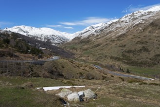 Großes Tal in den Bergen mit verschneiten Gipfeln, einer Straße und bewölktem Himmel, nördlich von