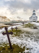 Gimsøy church with cemetery, snow-covered mountains in the background, winter, Gimsøya, Lofoten,