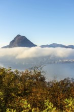 Mountain Peak San Salvatore Above Cloudscape and Lake Lugano with Sunlight and Clear Sky in City of