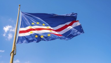 The flag of Cape Verde flutters in the wind, isolated against a blue sky