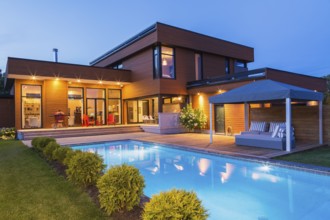 Rear of modern cube style home with stained horizontal wood cladding, in-ground swimming pool and