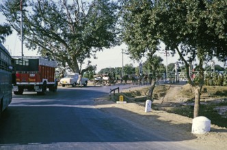 Fahrzeuge, die an einem Bahnübergang warten, ländliches Indien, wahrscheinlich Uttar Pradesh im