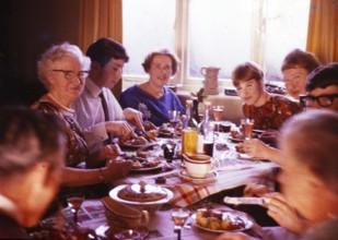 Traditional family Christmas meal all sitting around table eating and drinking, c 1960, England, UK