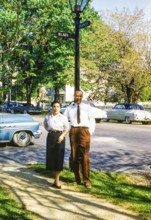 Full-length portrait of an elegantly dressed man and woman standing on the street next to a