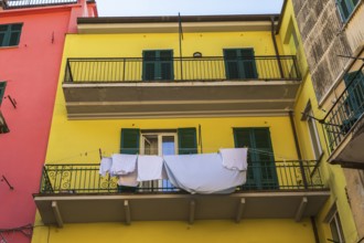 Yellow residential apartment building facade with washed clothes and blue bed sheet drying on