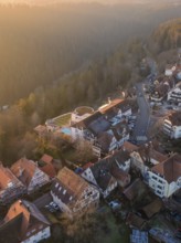 View of a village with half-timbered houses at sunrise in a hilly wooded area, Zavelstein, district