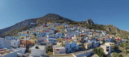 Panoramic view of the colourful village of Menetes stretching over a hill under a clear sky,