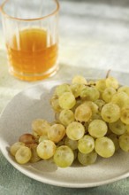 A branch of white grapes, on a gray plate, with a glass of white wine, top view, natural light,