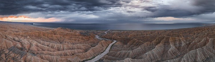 Panorama, landscape of eroded hills, badlands at sunset, Issyk Kul Lake in the background, aerial